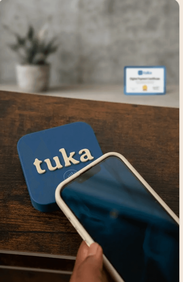 A guest tapping their phone against the Tuka NFC tag on a hotel room desk
